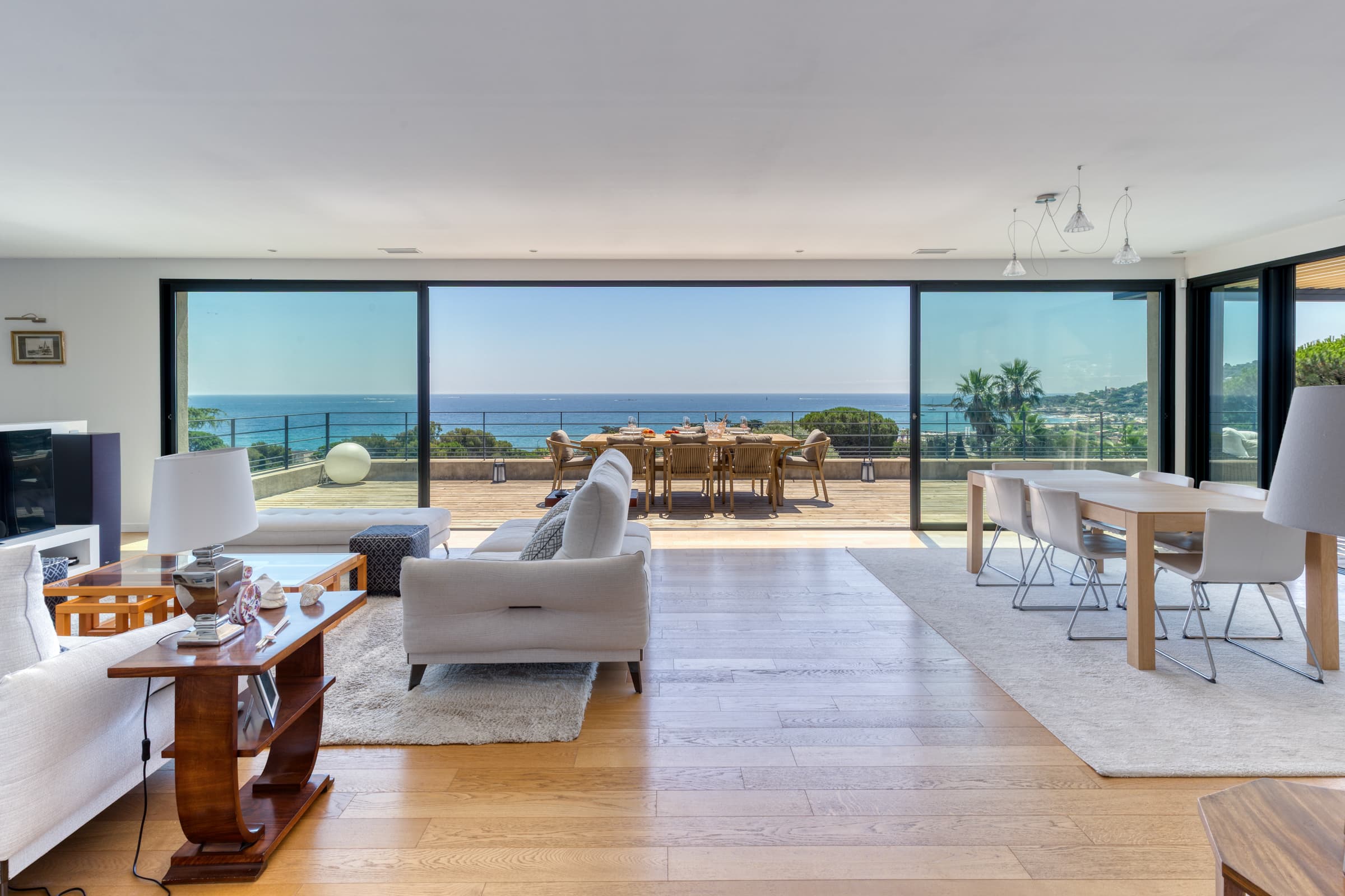 Pièce de vie spacieuse et élégante dans villa contemporaine à Sainte-Maxime, ouverte sur la terrasse avec vue panoramique sur la mer.