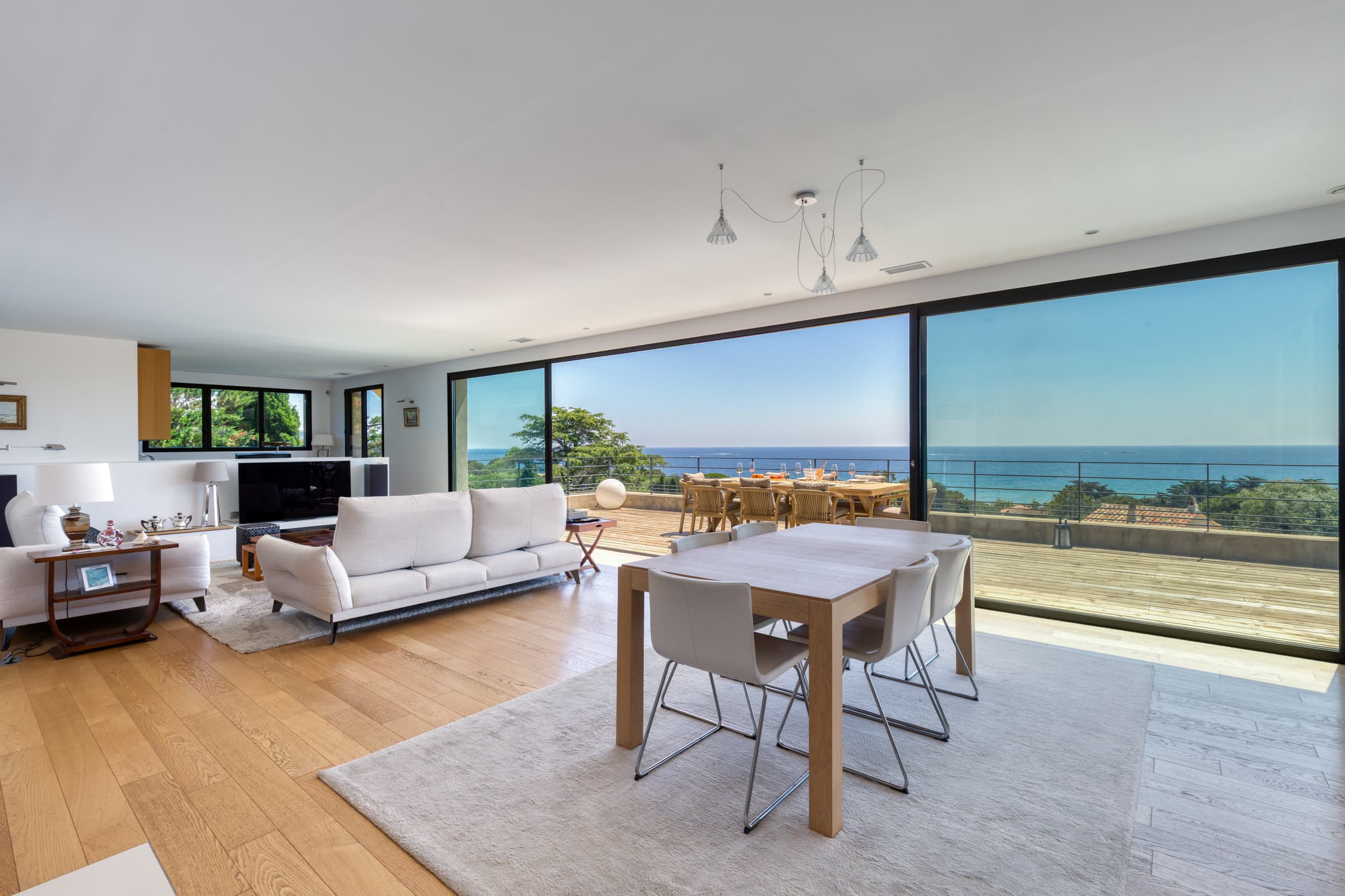 Pièce de vie spacieuse et élégante dans villa contemporaine à Sainte-Maxime, ouverte sur la terrasse avec vue panoramique sur la mer.