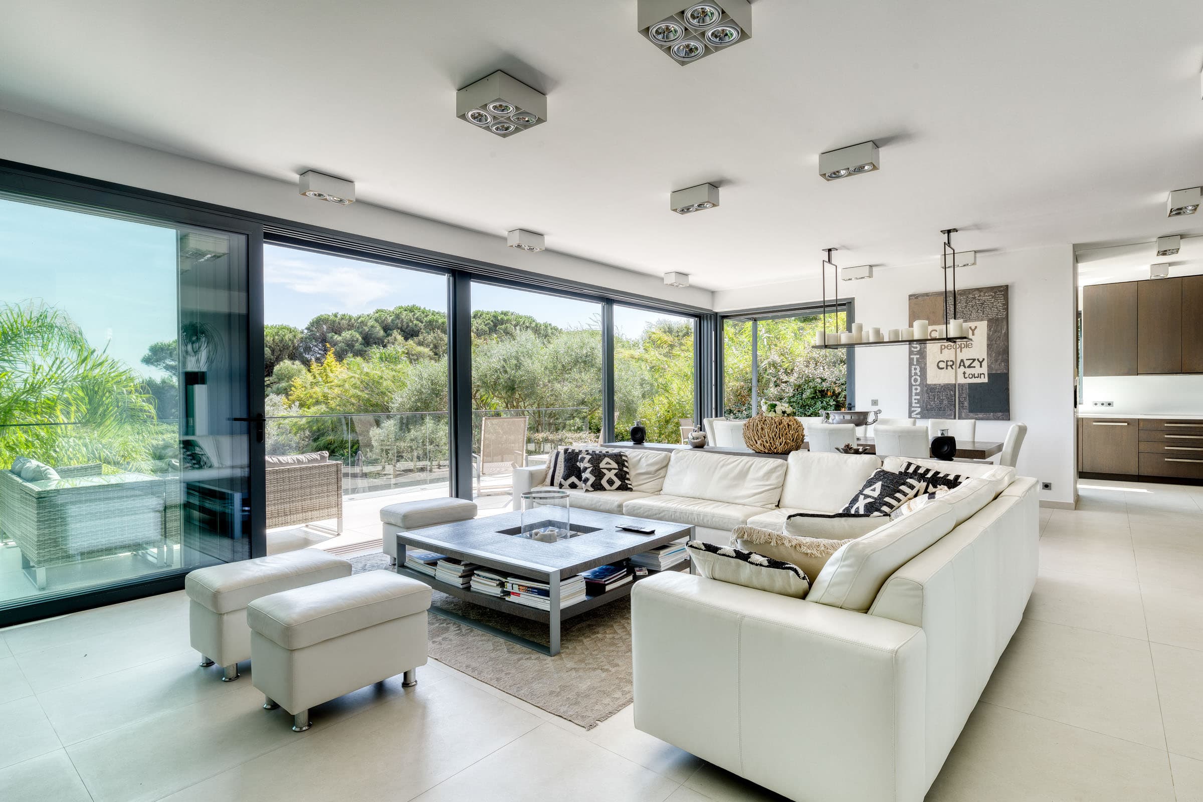 Grand salon moderne avec baies vitrées donnant sur le jardin, villa à vendre à Ramatuelle près des plages et du Club 55.