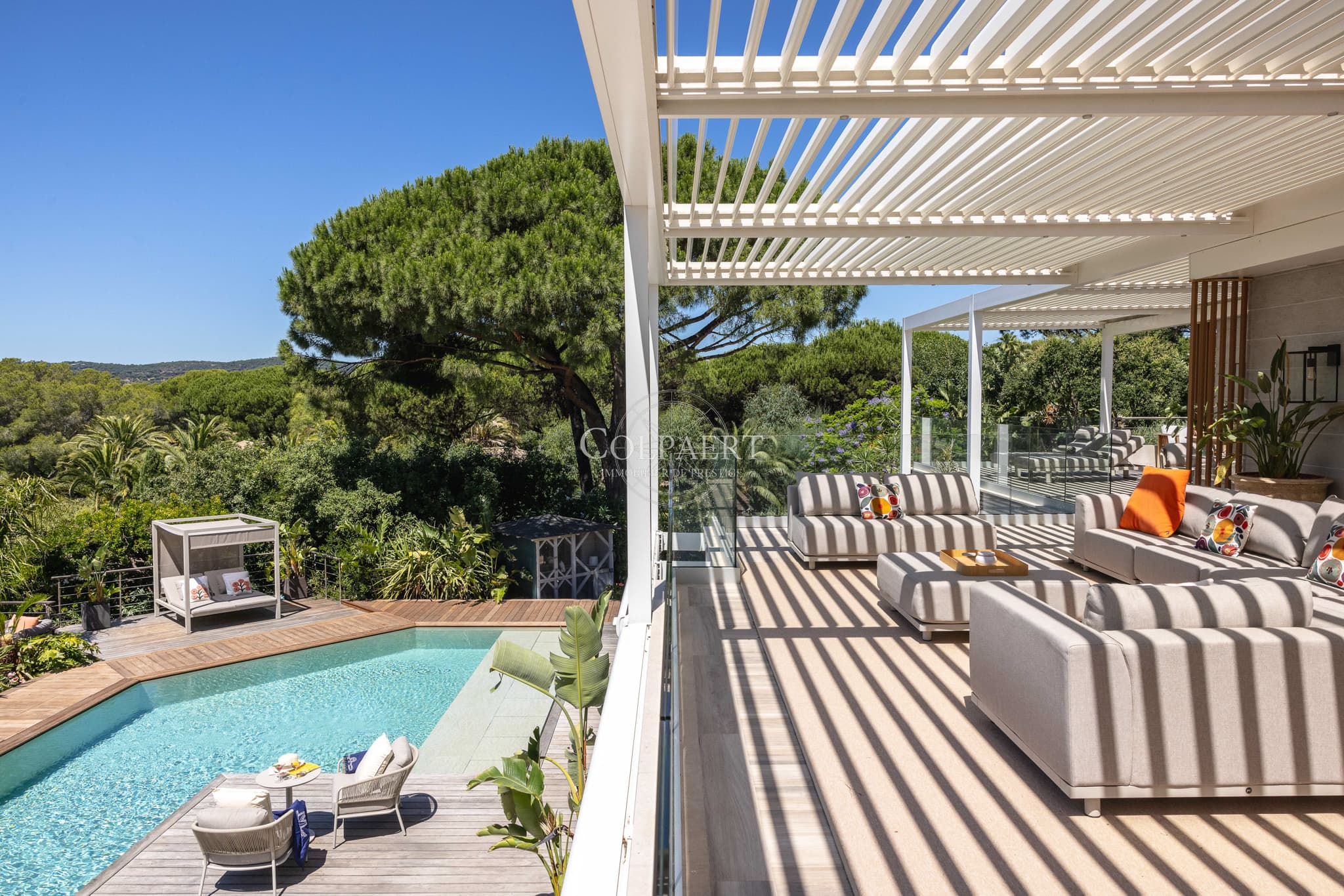 Terrasse ensoleillée offrant une vue dégagée sur la piscine et les jardins paysagers d'une propriété de prestige près des plages de Pampelonne.