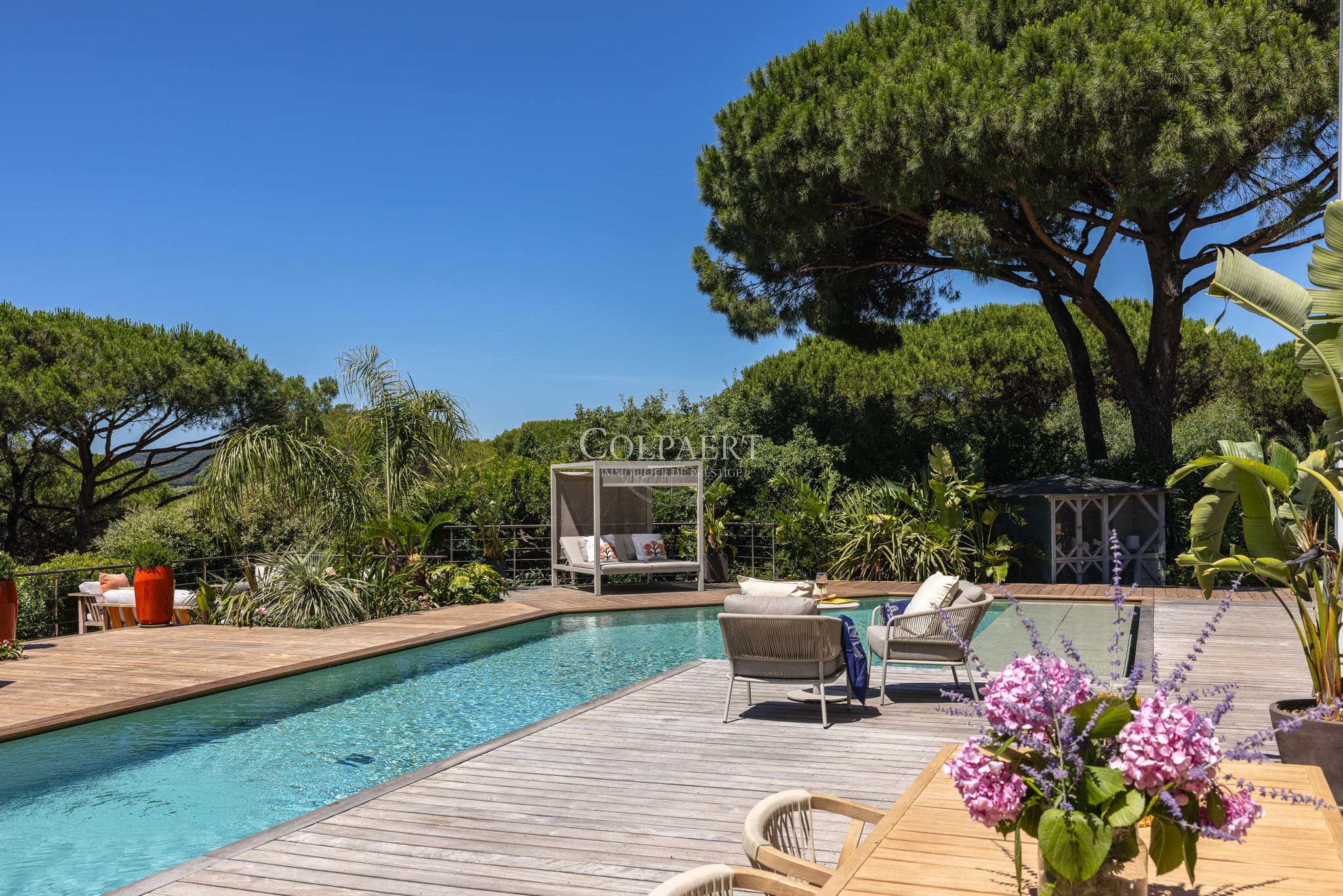 Terrasse ensoleillée offrant une vue dégagée sur la piscine et les jardins paysagers d'une propriété de prestige près des plages de Pampelonne.