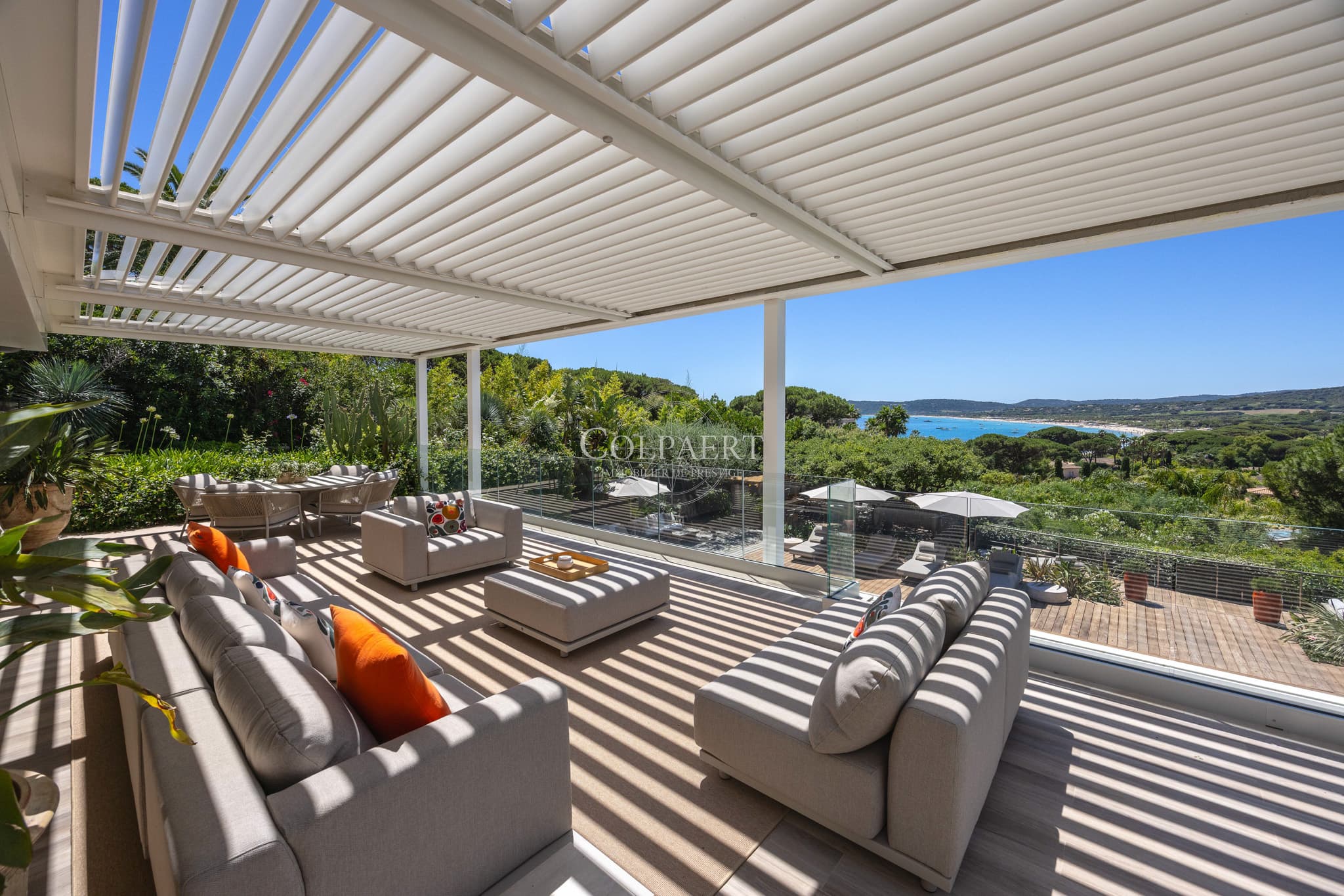 Terrasse ensoleillée offrant une vue dégagée sur la piscine et les jardins paysagers d'une propriété de prestige près des plages de Pampelonne.