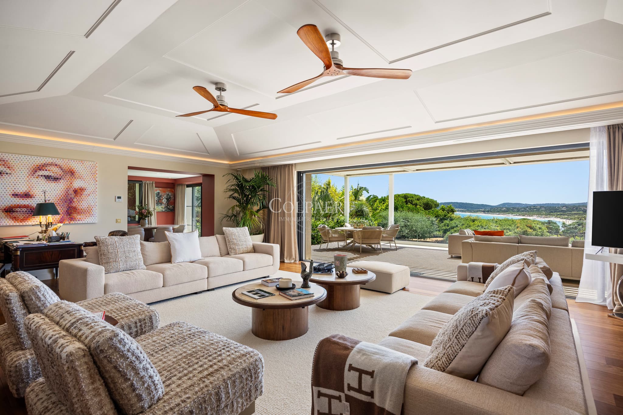 Salon de style colonial baigné de lumière, ouvert sur les terrasses avec une vue exceptionnelle sur la Méditerranée.