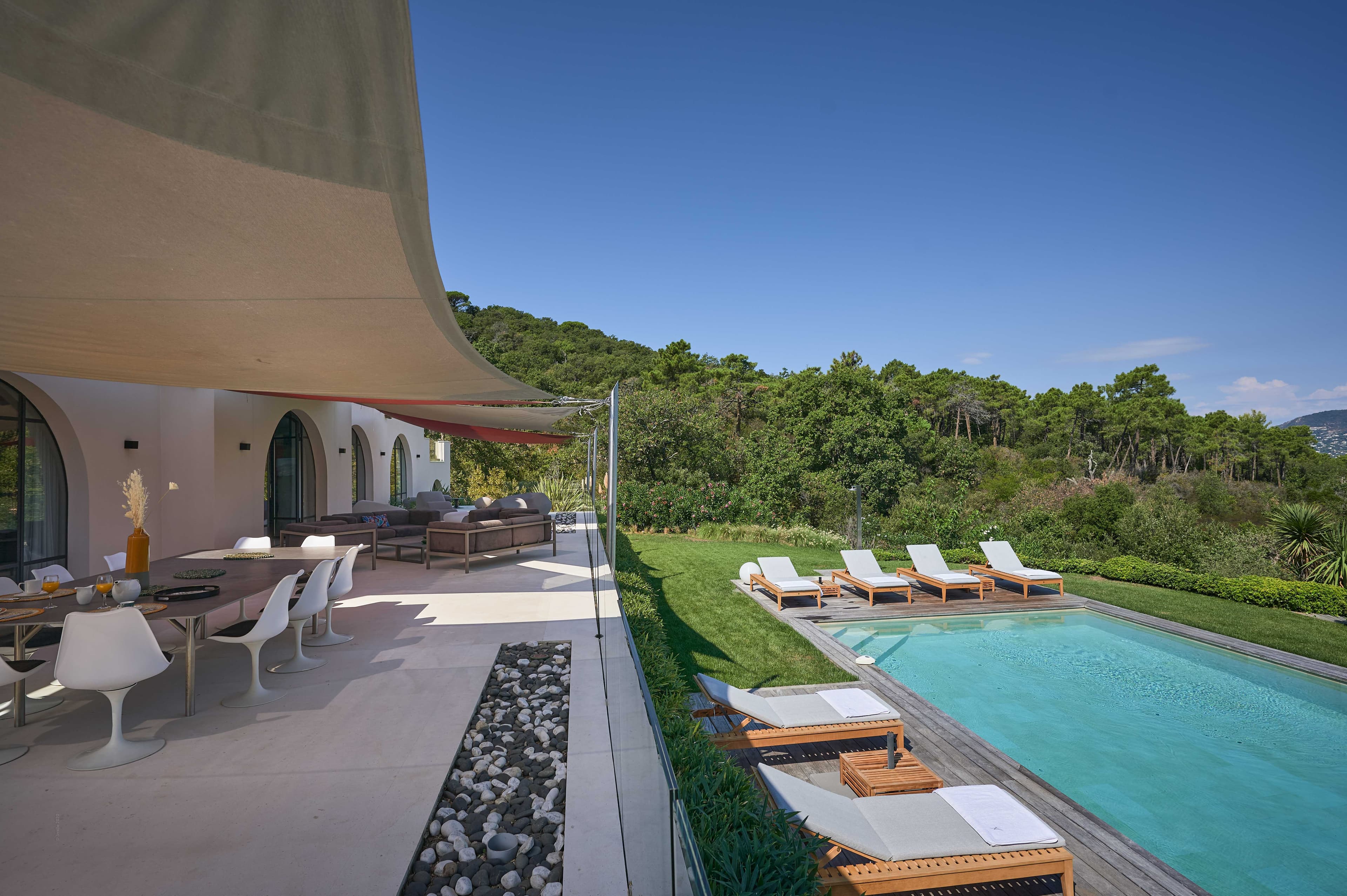 Piscine entourée de terrasses en bois exotique et jardin paysager dans une villa d’exception proche de Pampelonne.