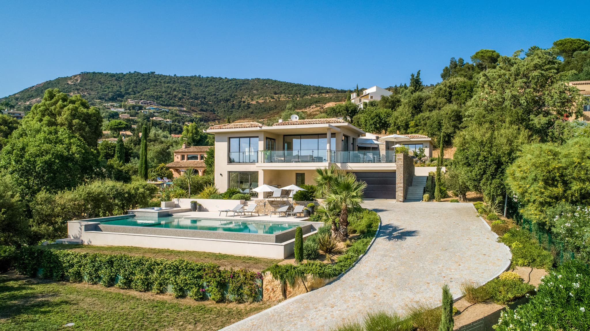Vue sur la façade principale de la villa d’exception avec piscine à débordement dans le Golfe de Saint-Tropez