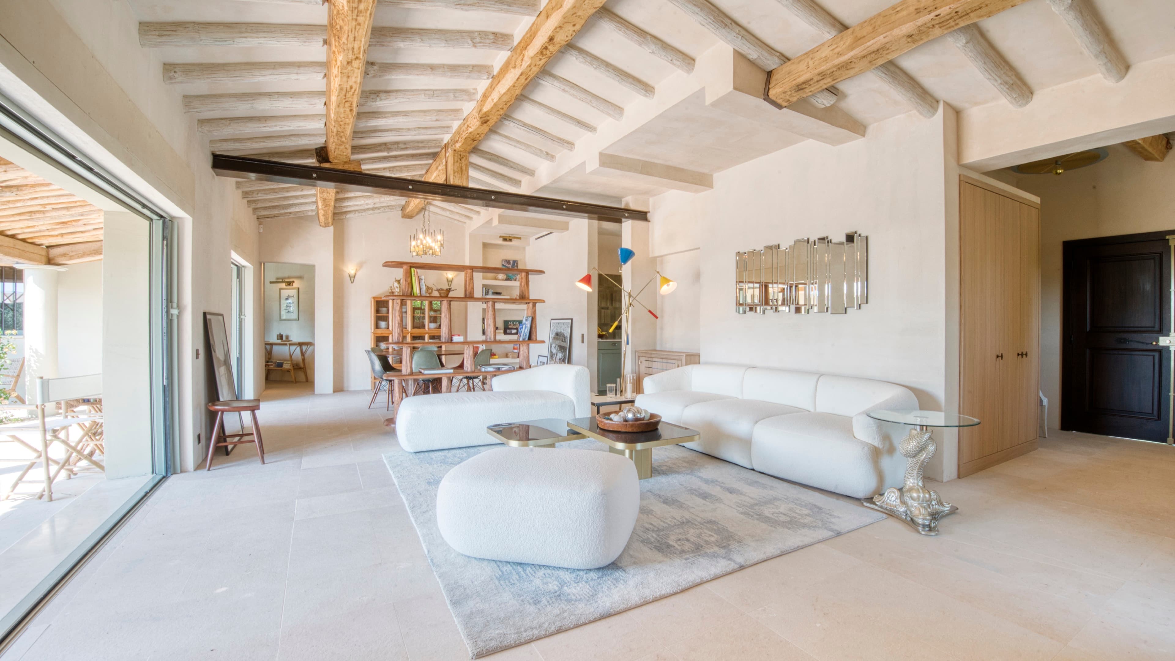 Salon raffiné baigné de lumière naturelle, offrant une ambiance provençale et conviviale à Ramatuelle.