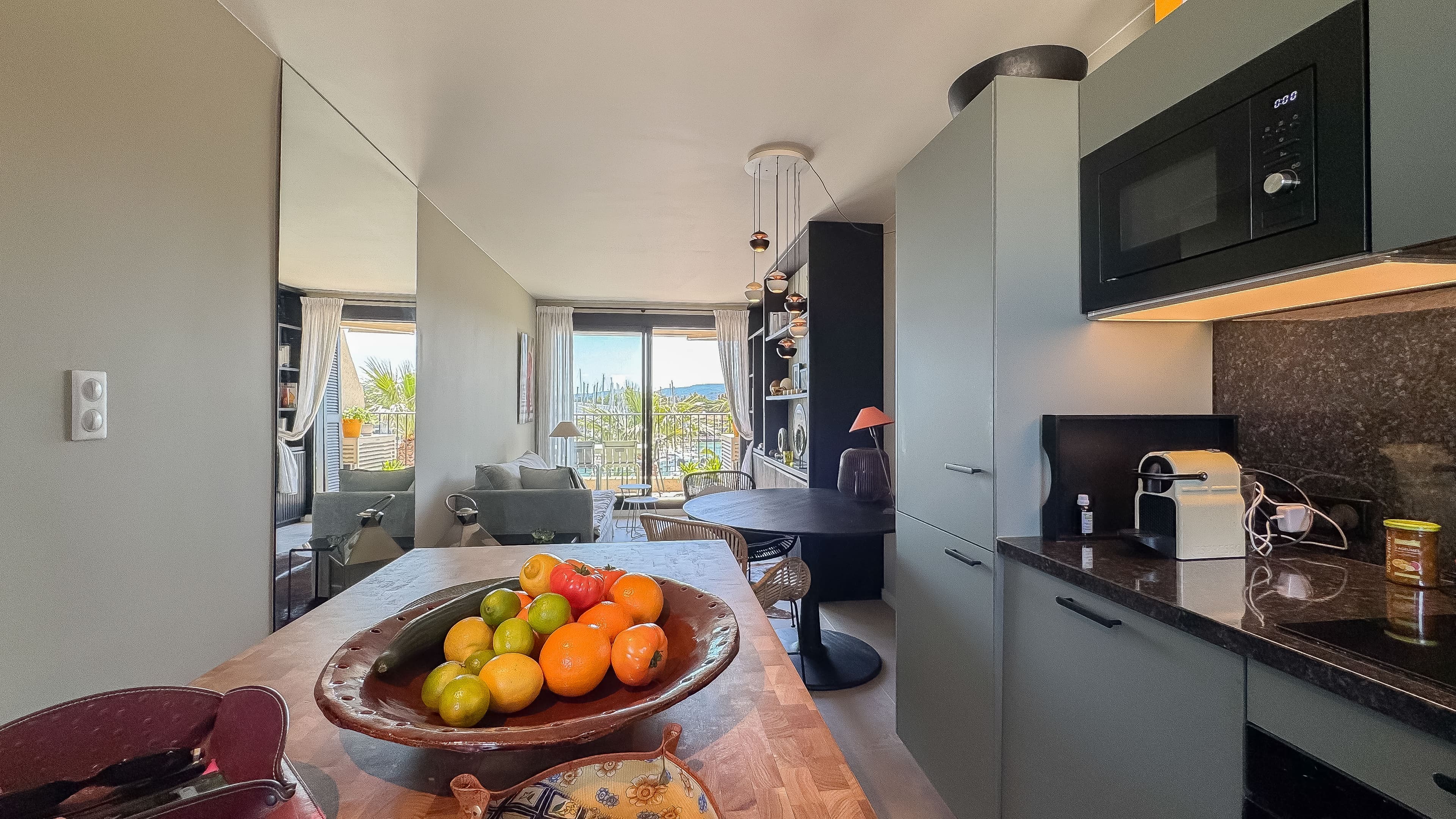 Cuisine entièrement équipée dans un appartement à vendre à Les Marines de Cogolin, ouverte sur le séjour et offrant une vue sur le port de plaisance.