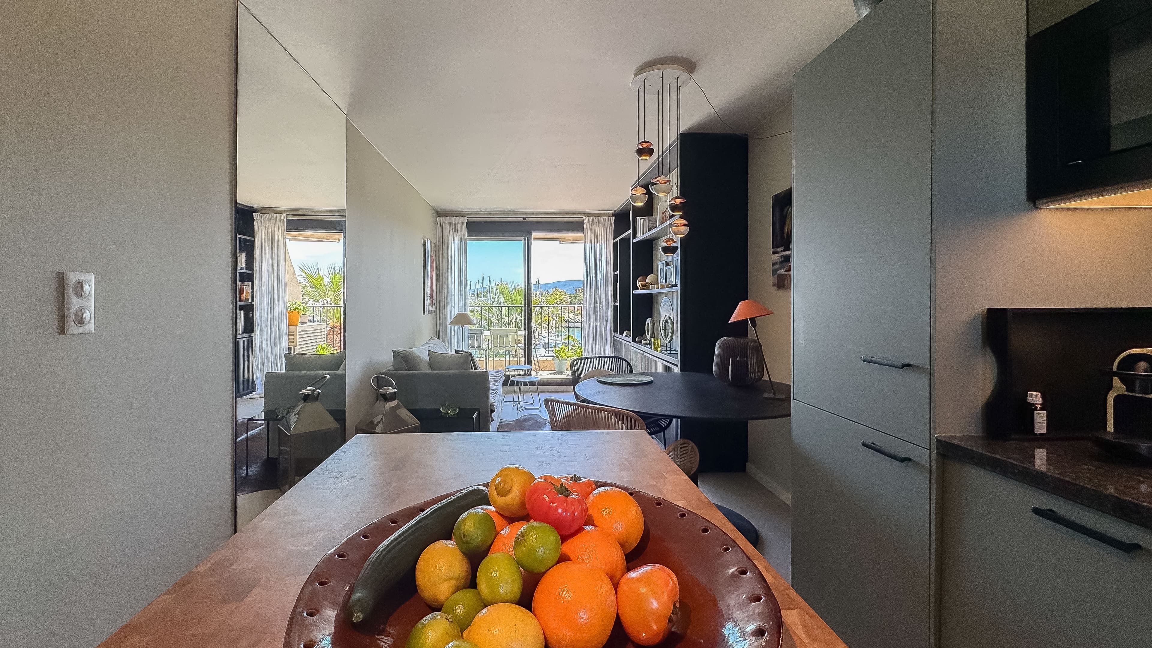 Cuisine entièrement équipée dans un appartement à vendre à Les Marines de Cogolin, ouverte sur le séjour et offrant une vue sur le port de plaisance.