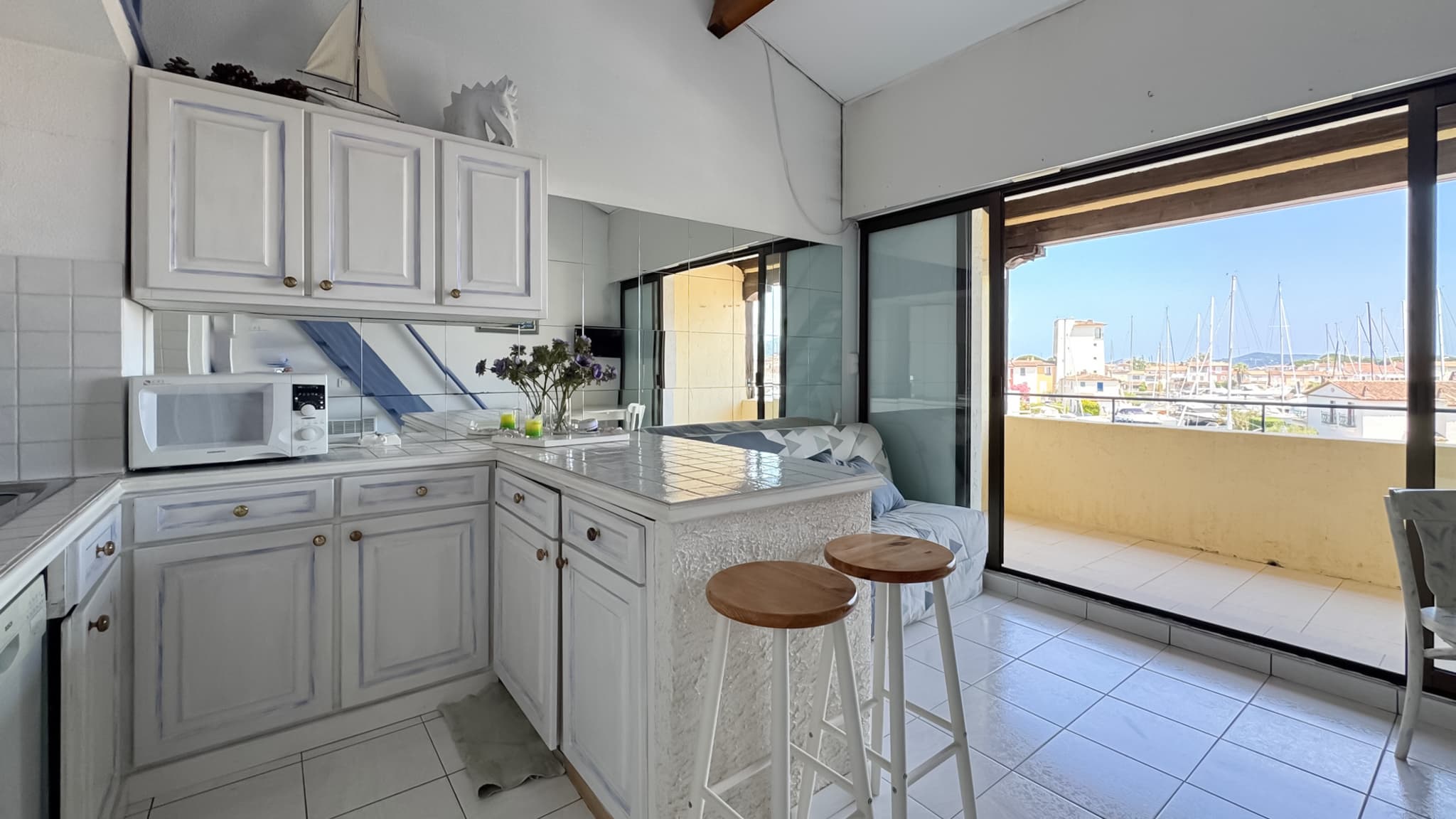 Cuisine ouverte fonctionnelle dans un appartement en vente à Port-Grimaud, connectée au séjour avec vue port.