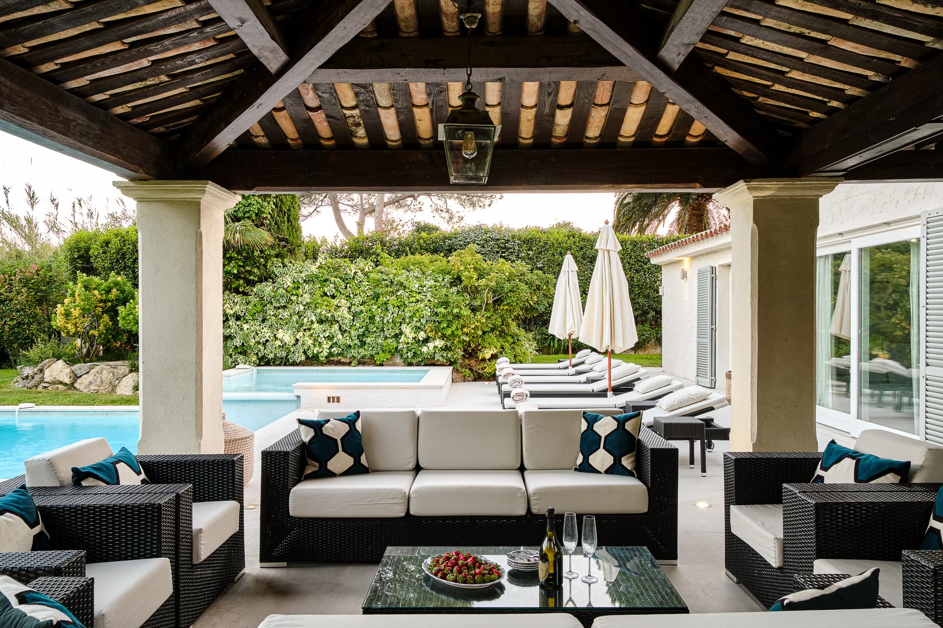 Élégante terrasse couverte avec espace repas extérieur donnant sur le jardin et la piscine.