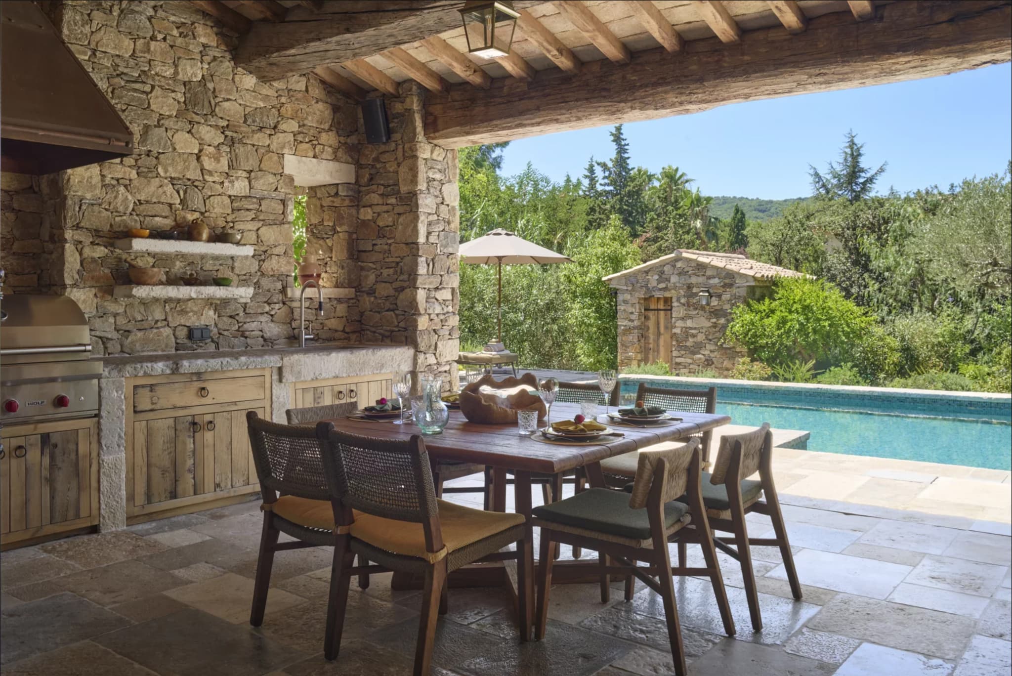 Cuisine d’été avec barbecue Wolf et rangements, face à la piscine chauffée, dans une villa de luxe à vendre à Saint-Tropez.