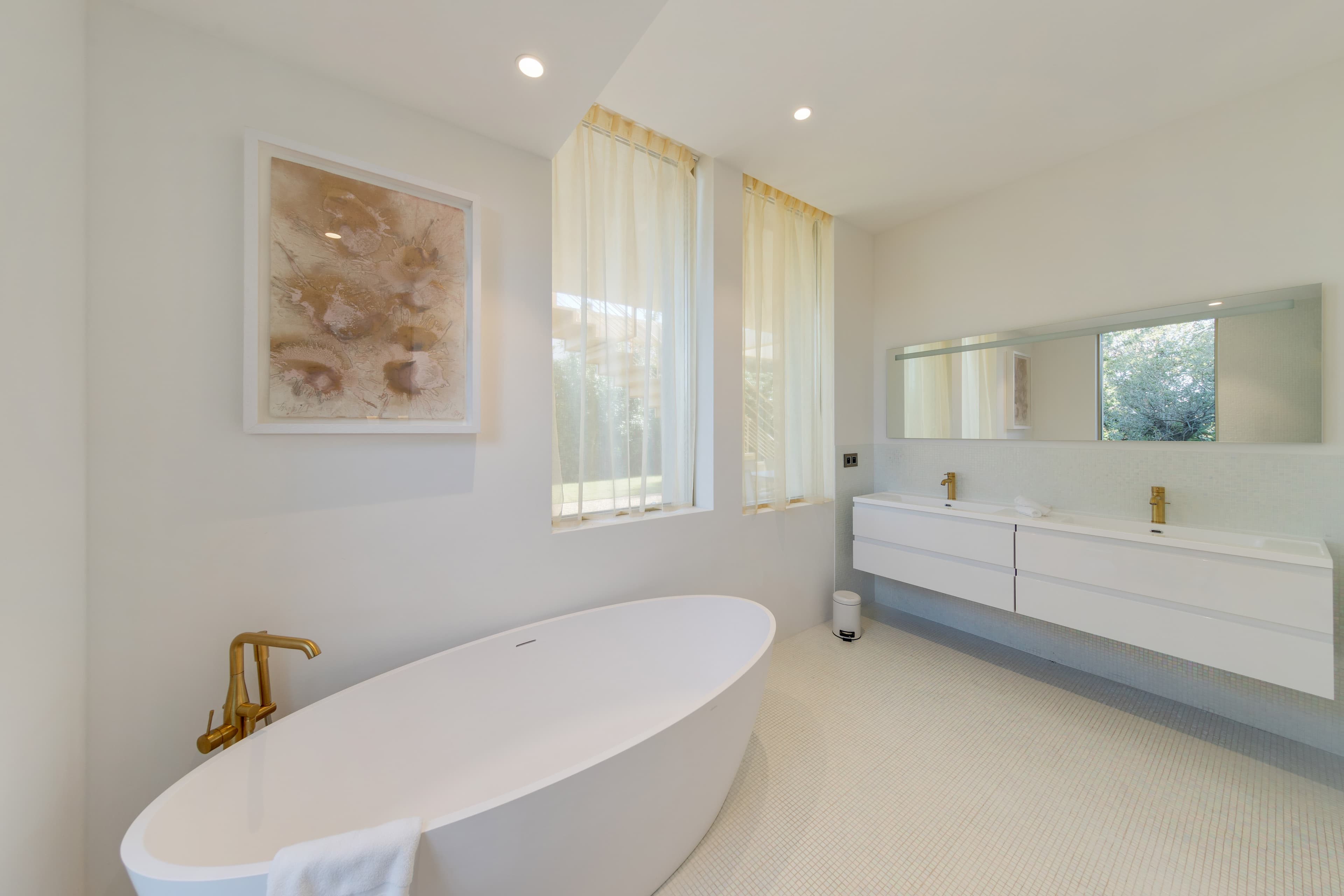 Salles de bain élégantes avec mosaïques blanches et détails dorés. Raffinement et luxe dans villa contemporaine à Saint-Tropez.