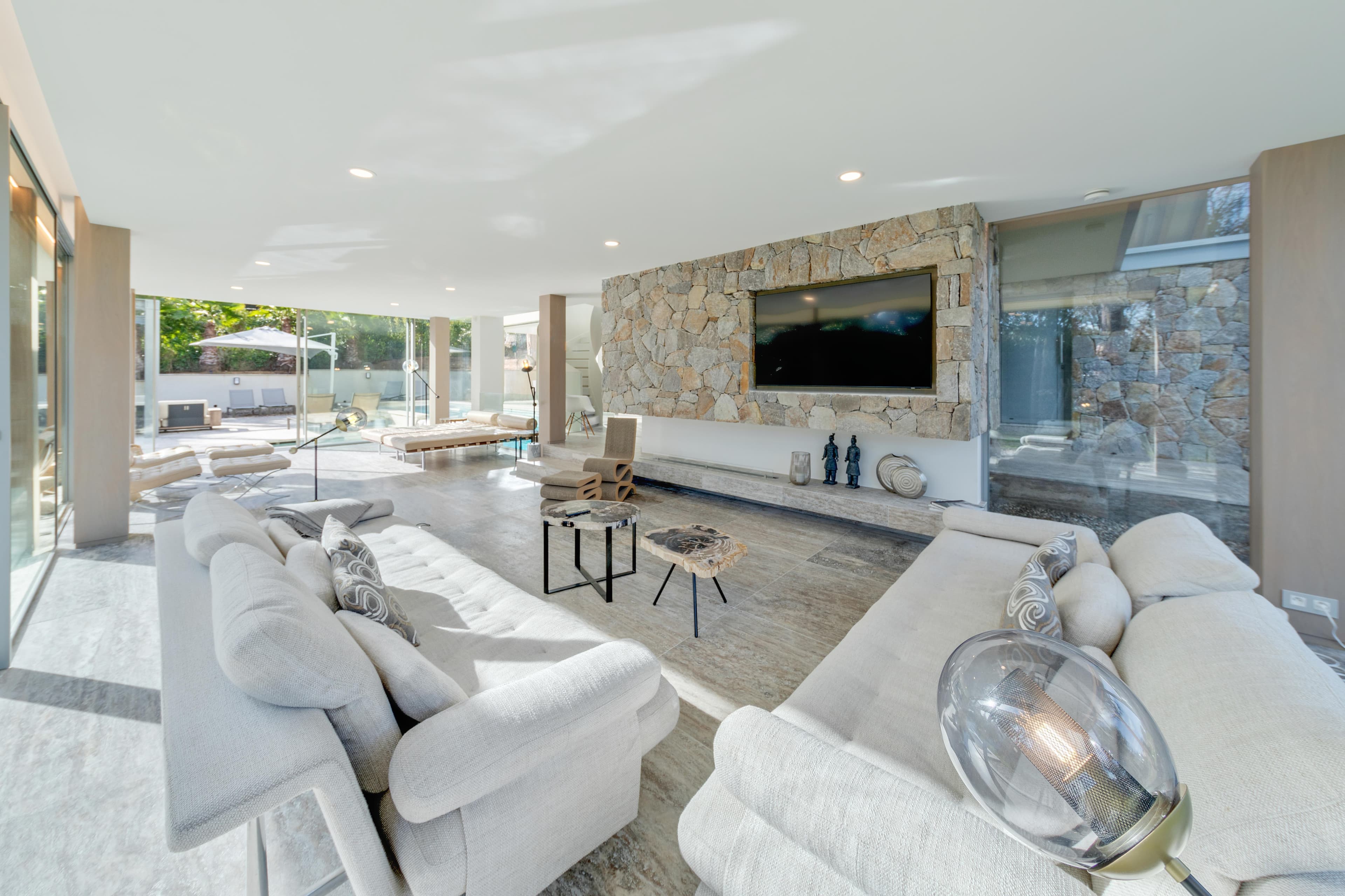 Vaste salon avec canapés et grandes baies vitrées ouvrant sur la terrasse. Villa moderne à vendre à Saint-Tropez.