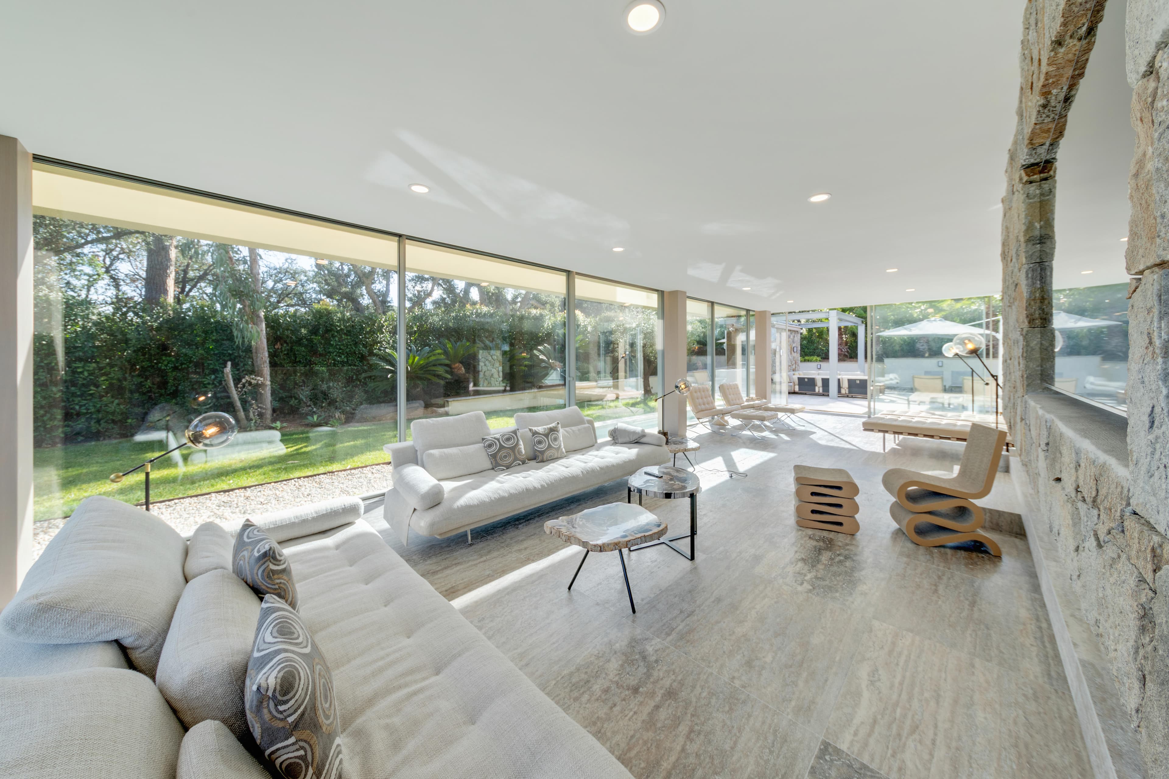 Vaste salon avec canapés et grandes baies vitrées ouvrant sur la terrasse. Villa moderne à vendre à Saint-Tropez.